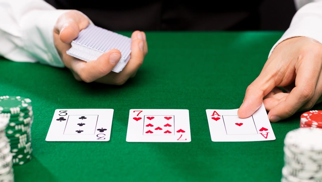 A dealer placing cards on the poker table.