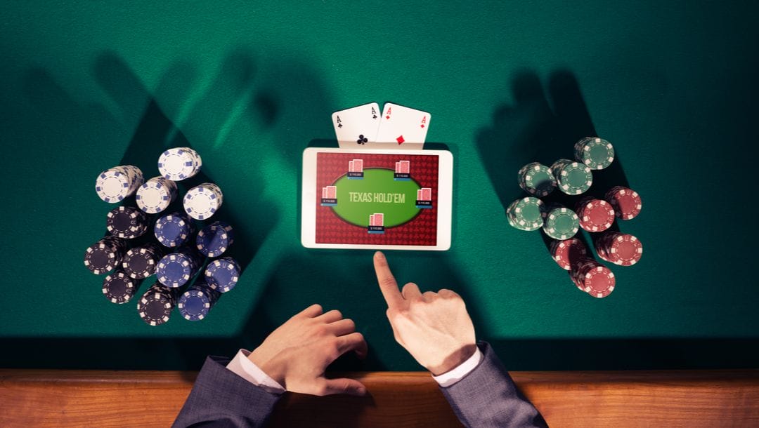 Texas Hold’em played on a tablet, with poker chips and cards on a real poker table.