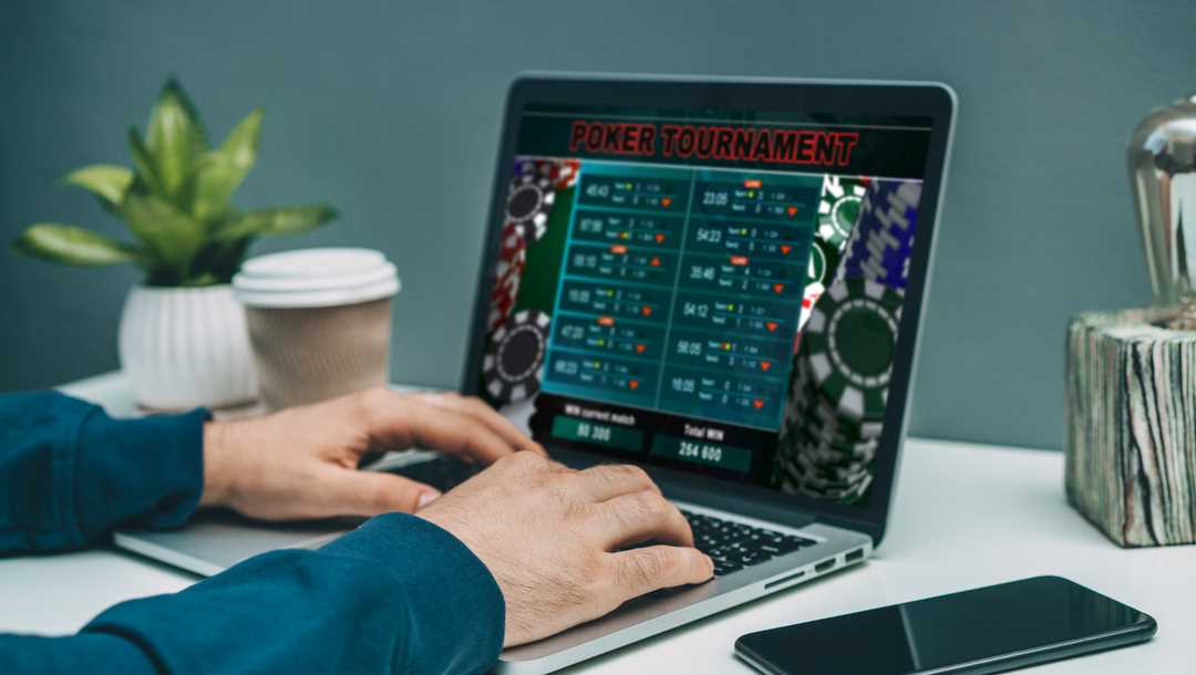 A man plays online poker on a laptop.