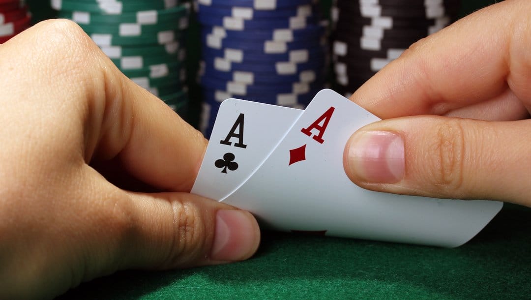A poker player takes a peek at their cards and sees two aces.
