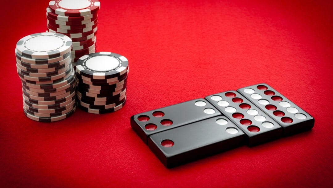 Pai gow tiles and poker chips on a red background.