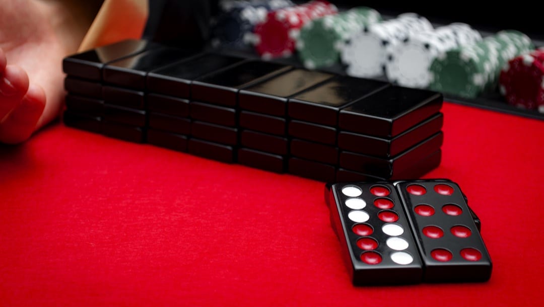 A stack of pai gow tiles with poker chips on a table.