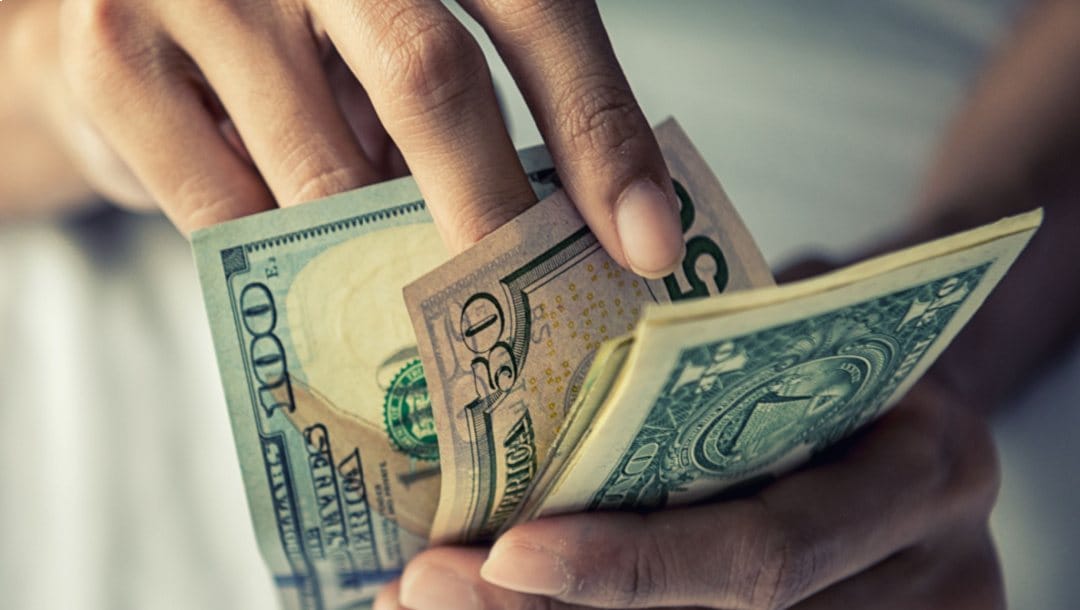 A closeup of hands counting American dollars.