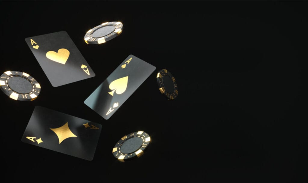 Black and gold playing cards and poker chips against black backdrop.