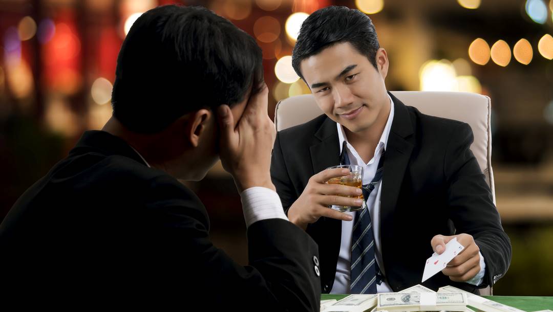 Two poker players in dark suits face off at the table.