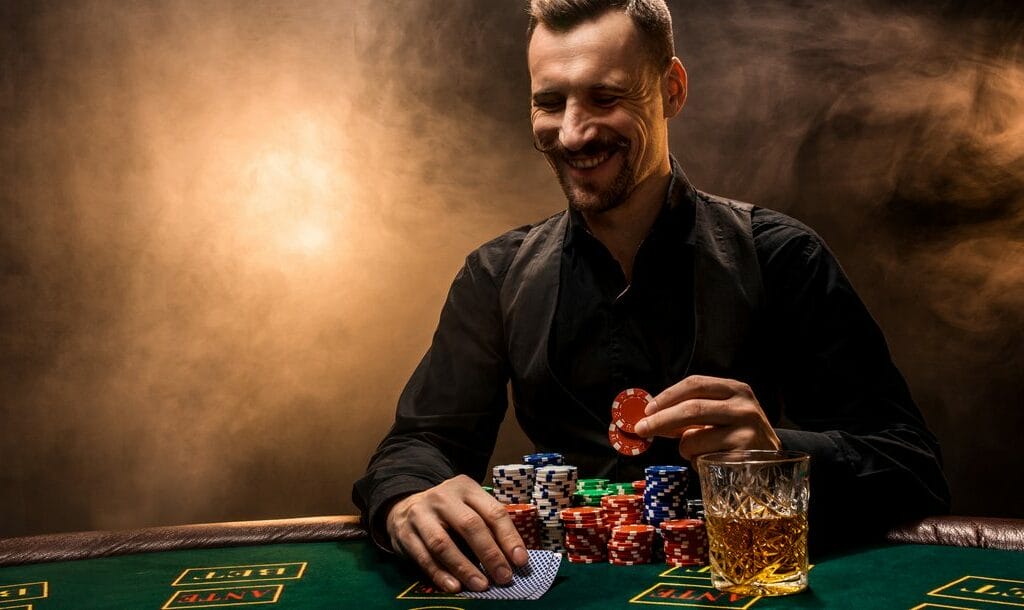 A poker player smiles as he checks his hole cards and looks to bet.