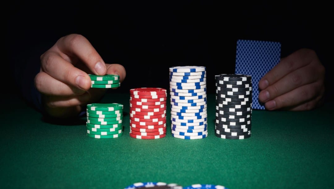 Poker chips and a man’s hands on a poker table.