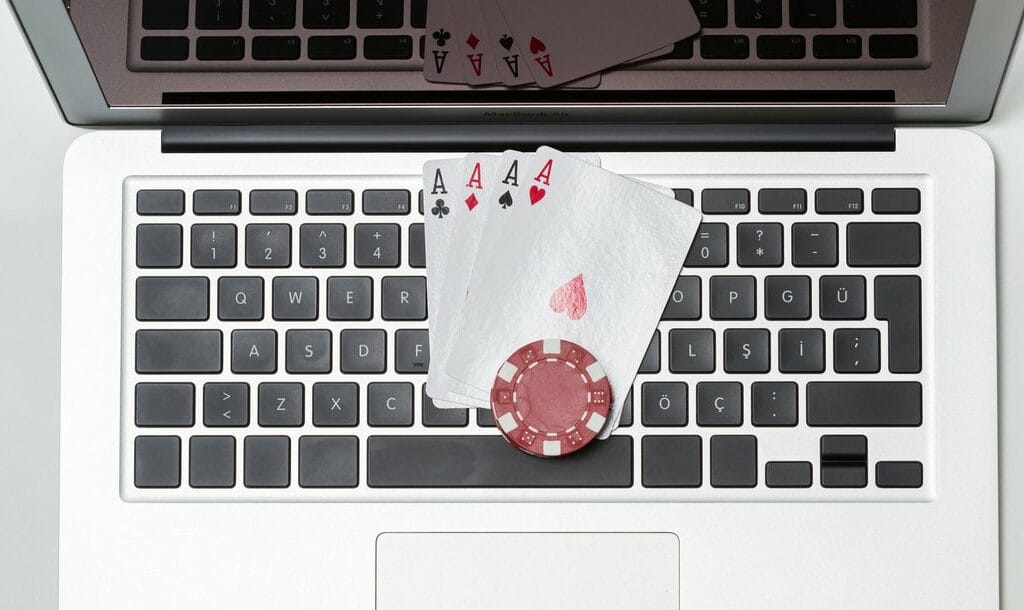 Four aces and a poker chip sit on a laptop keyboard.