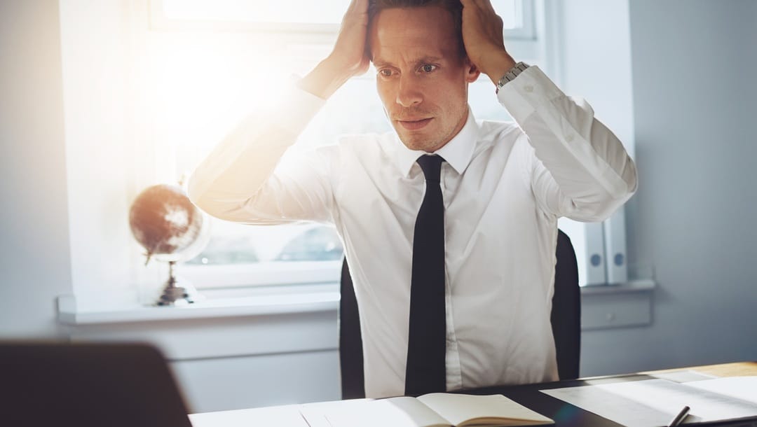 A businessman stares in shock at his laptop screen.