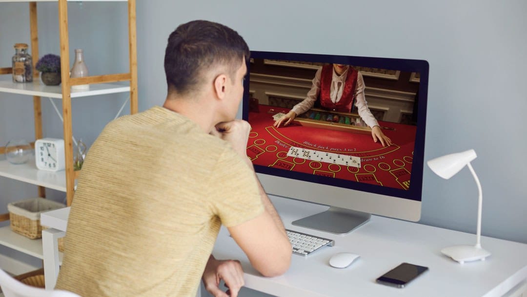 A man sitting in front of a computer playing an online poker game.