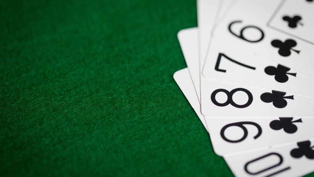 Playing cards spread out on a green felt table.