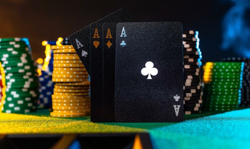 Black ace cards and colorful casino chips on a green felt table.