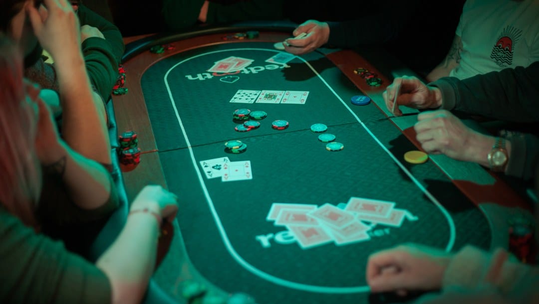 Poker players playing poker on a green felt table.