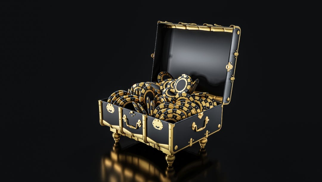 A stylish black and gold treasure chest filled with black and gold poker chips against a black background.