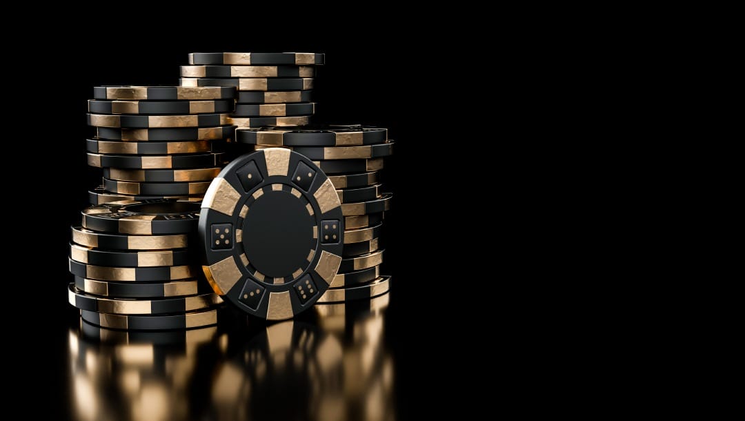 A stack of black and gold poker chips against a black background.