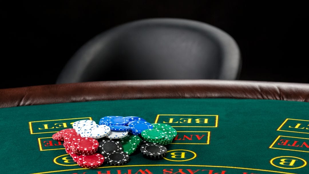Poker chips of different colors on the green surface of a poker table.