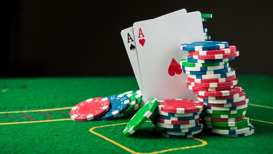 Poker chips and two ace playing cards on a green felt table.