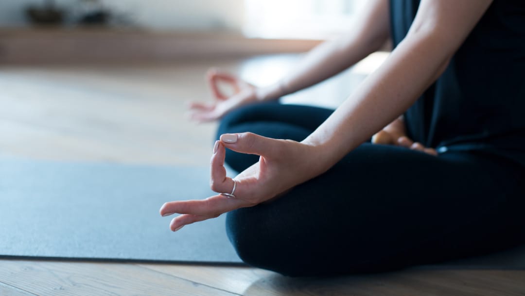 A woman meditating on a yoga mat.