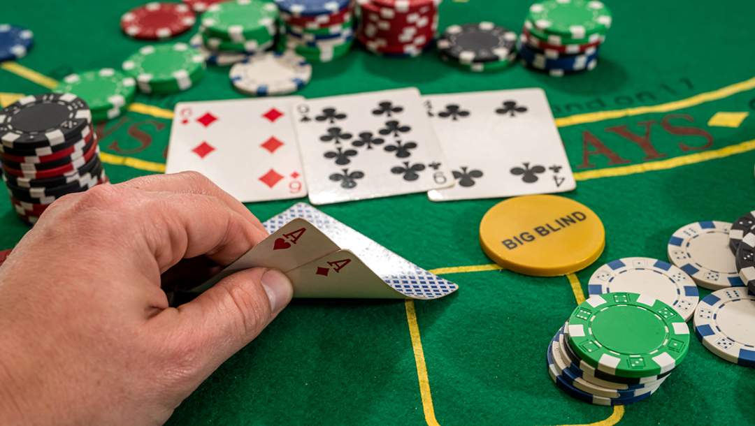 A person looks at their hand on a poker table.