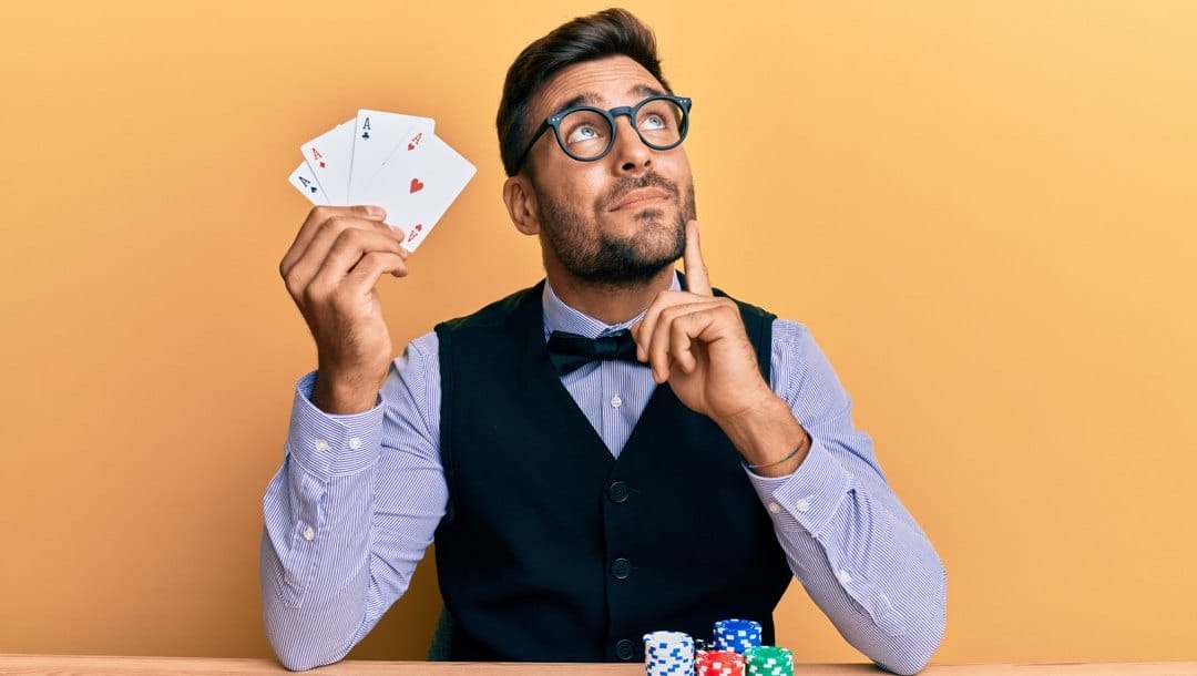 A poker player reveals his hand – four aces.