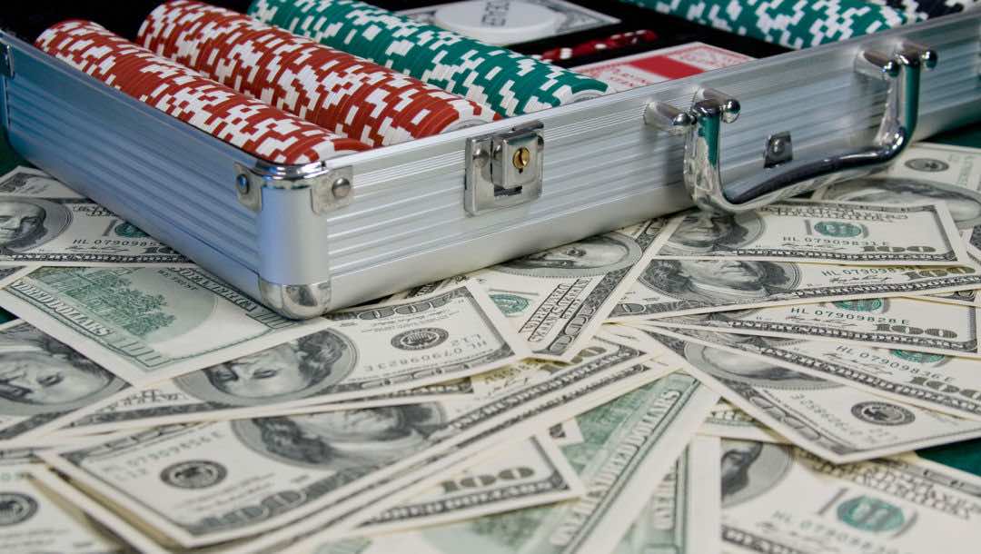 Dollar bills scattered around a poker case full of chips.