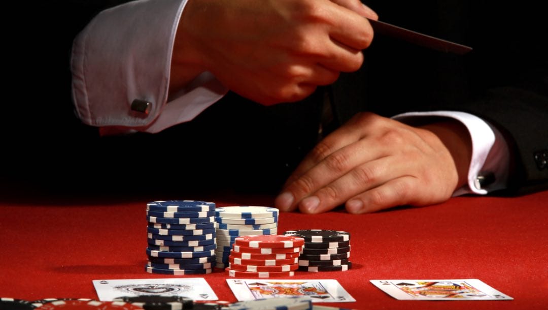 A man at a red poker table folds during a poker match.
