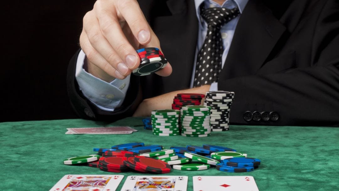 A man places chips on a green poker table.