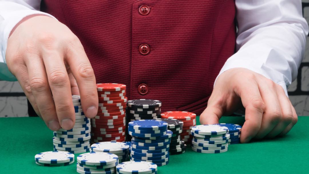 A dealer handles chips on the poker table.