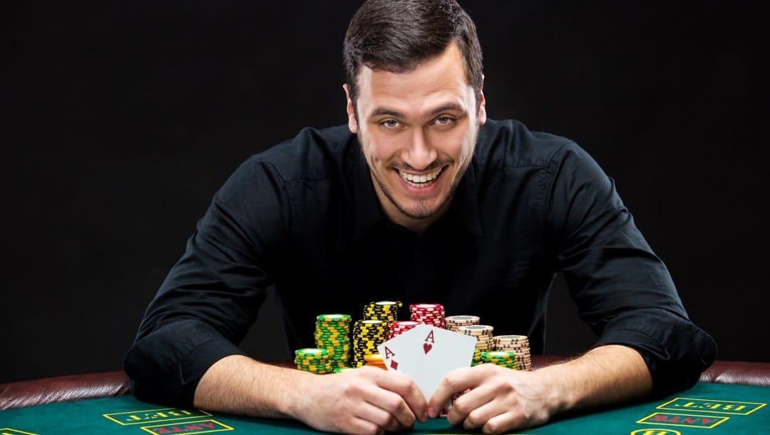 A smiling poker player reveals two aces.
