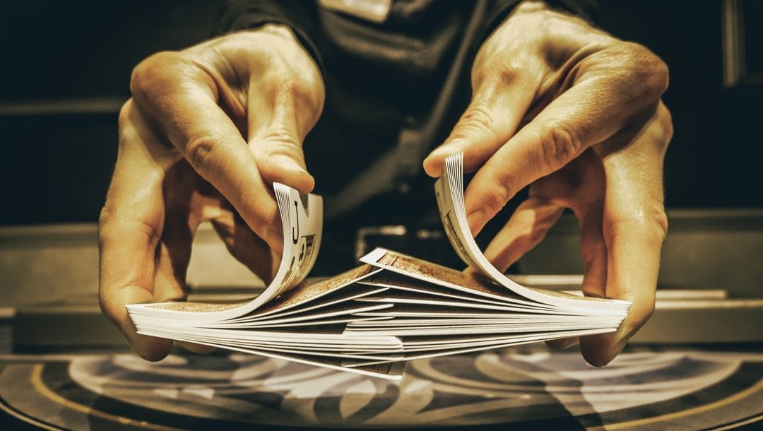 A casino dealer shuffles a deck of cards.