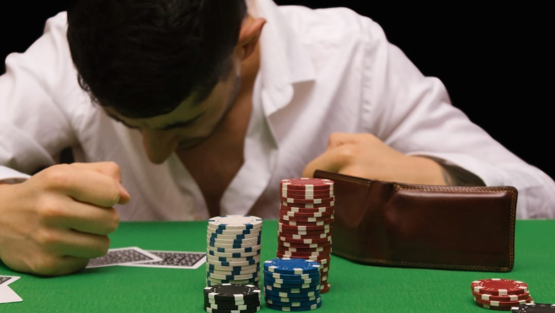 A man looks down at his playing card with disappointment.