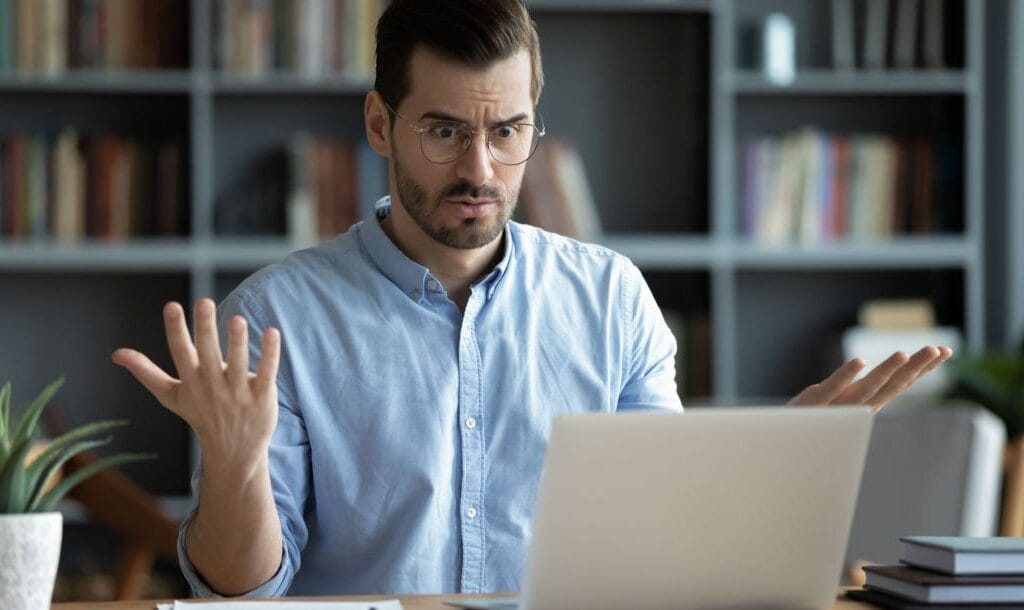 A businessman looking at his laptop in frustration.