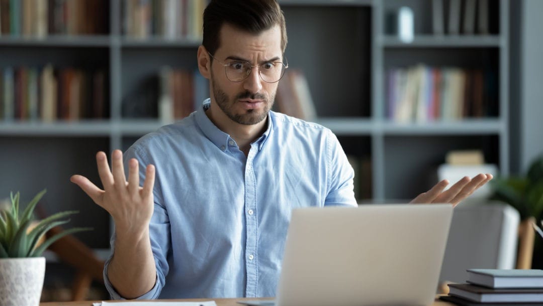 A businessman looking at his laptop in frustration.