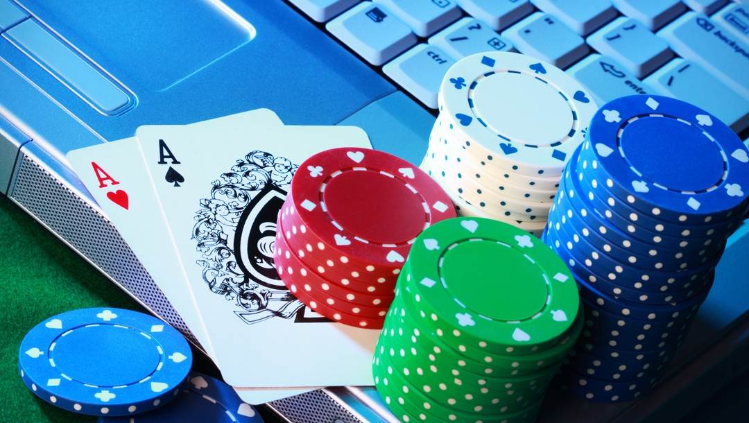 A pair of aces and stacks of poker chips on a laptop keyboard.