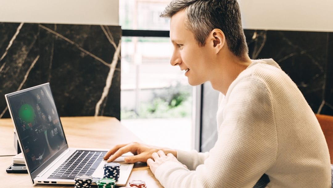 A man plays poker on his laptop.