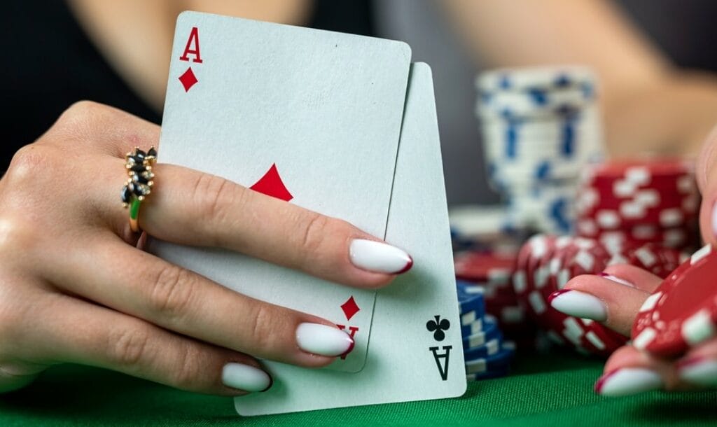 A woman holds up two aces during a poker game.