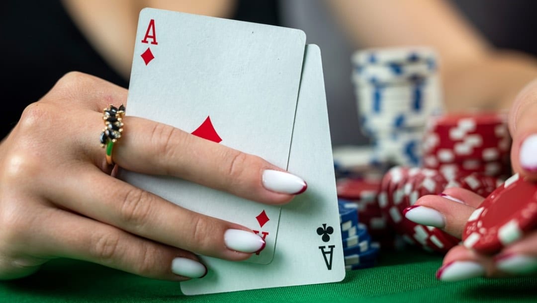 A woman holds up two aces during a poker game.