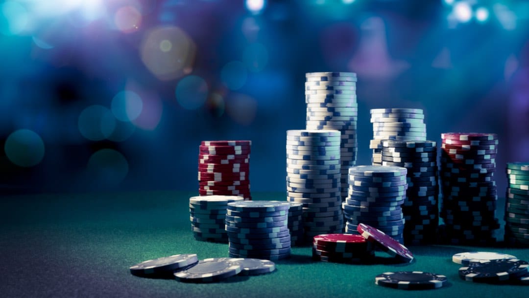 Several poker chip stacks on a poker table against a bokeh background.