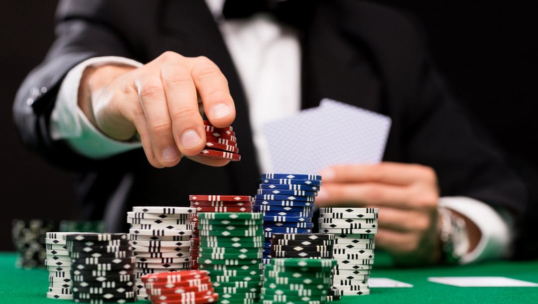 A player puts more chips on a stack of poker chips.