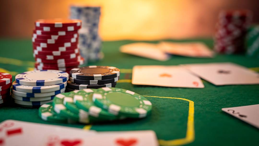 Stacks of poker chips and playing cards on a casino game table.