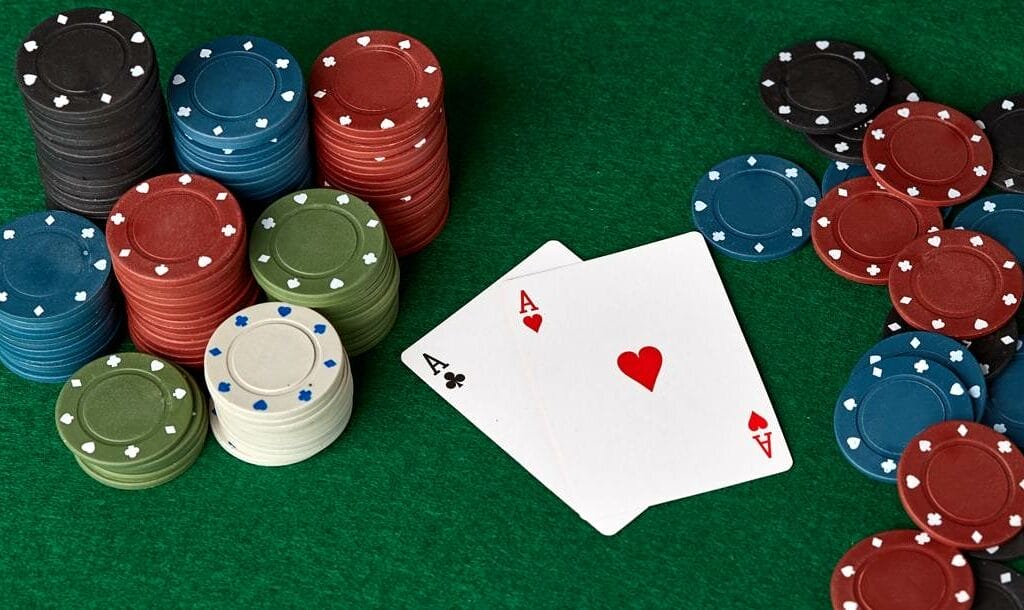 A pair of aces in-between poker chips.