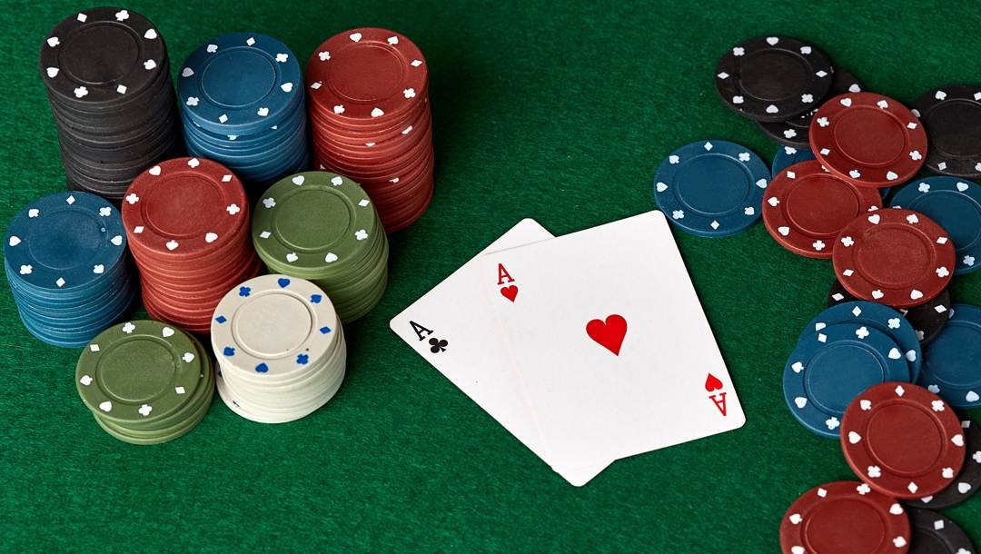 A pair of aces in-between poker chips.