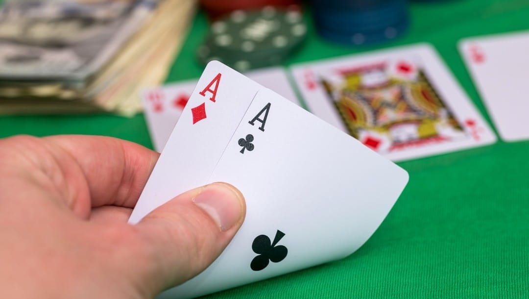 A poker player checks their hole cards and sees two aces.