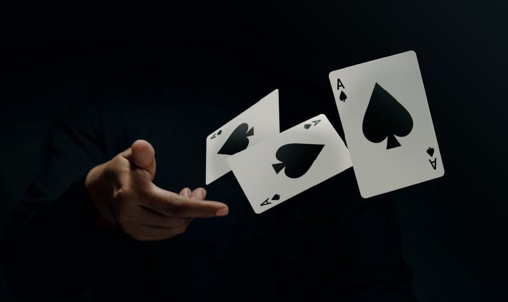 A hand throwing three ace of spades cards.