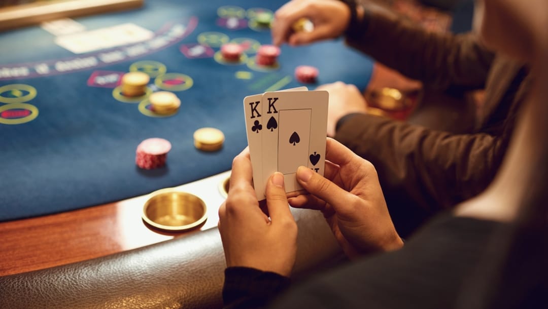 A poker player holds two kings at a poker table in a casino.