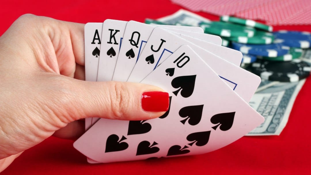 A woman holding playing cards on a red felt table.