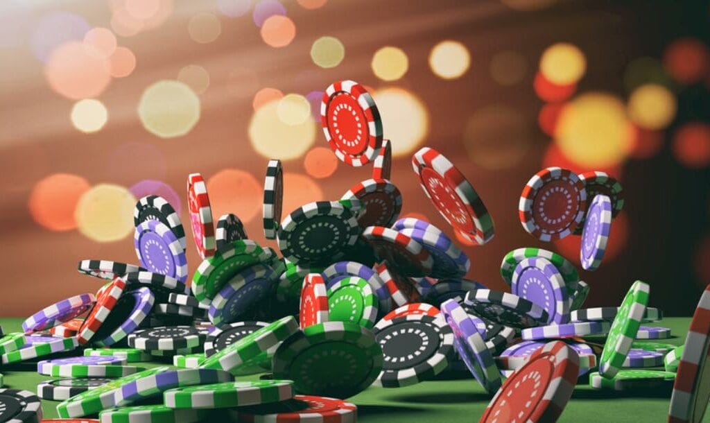 A variety of poker chips falling onto a poker table.