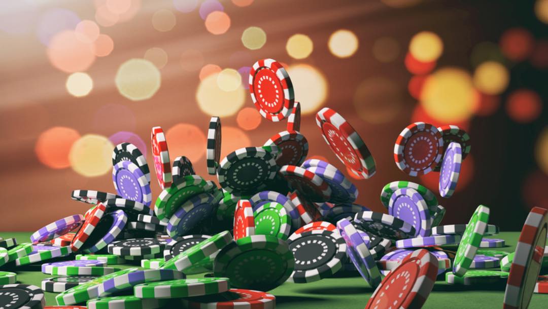 A variety of poker chips falling onto a poker table.
