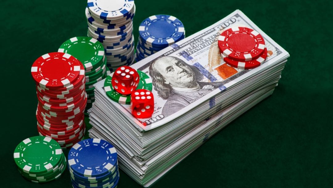 Poker chips on top of and around a stack of cash.