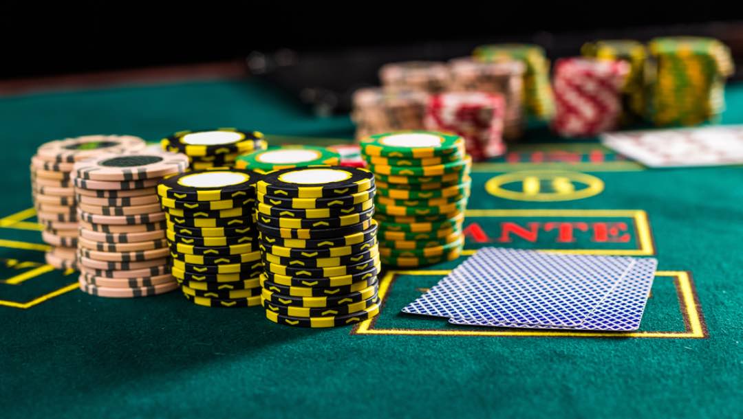 A stack of poker chips next to some cards on a table.
